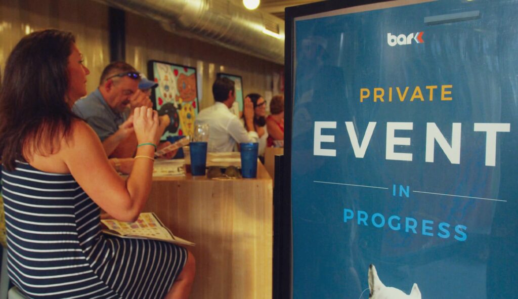 Person sitting at a table, sign that says "Private Events"